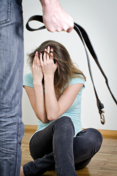 Мужчина с ремнем идет к жене. Концепция домашнего насилия
