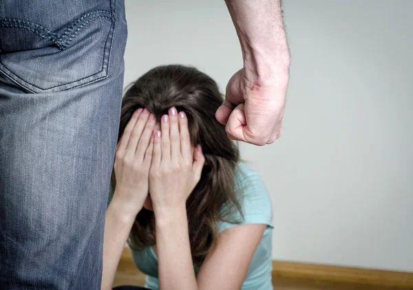 Концепция домашнего насилия. Испуганная женщина и мужской кулак — стоковое фото