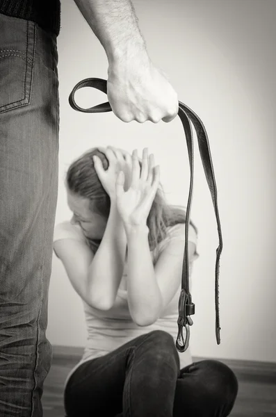 Hombre con cinturón acercándose a su esposa. Concepto de violencia doméstica. Blanco y negro —  Fotos de Stock