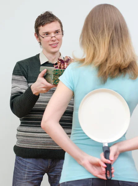 Woman hiding pan underhand talking to man — Stock Photo, Image