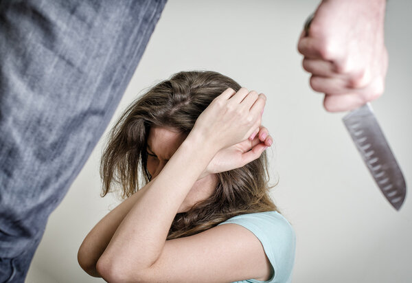 Мужчина с ножом идет к жене. Концепция домашнего насилия
