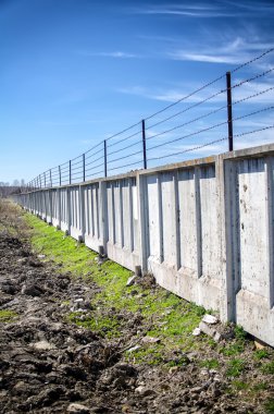 mavi gökyüzünün altında dikenli tel çit