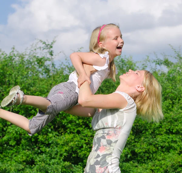 Moeder en dochter spinnen in zomer park — Stockfoto