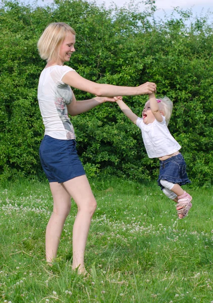 Moeder en dochter spinnen in zomer park — Stockfoto