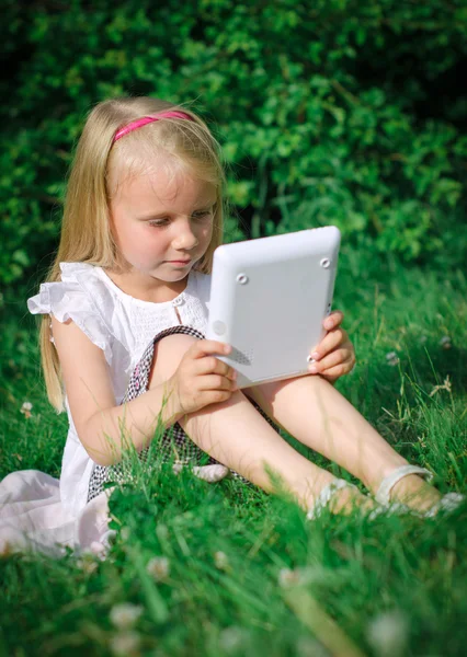 Little girl sitting with computer outdoors. — Stock Photo, Image