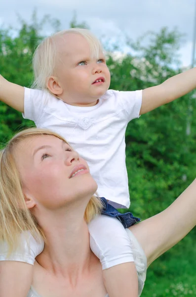 Happy mother carrying her daughter on shoulders — Stock Photo, Image