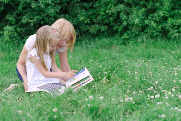 Mother and daughter reading book in the park — Stock Photo, Image