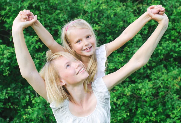 Happy mother carrying her daughter on shoulders — Stock Photo, Image