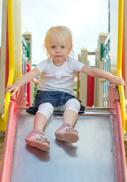 Маленькая девочка на детской горке на детской площадке — стоковое фото