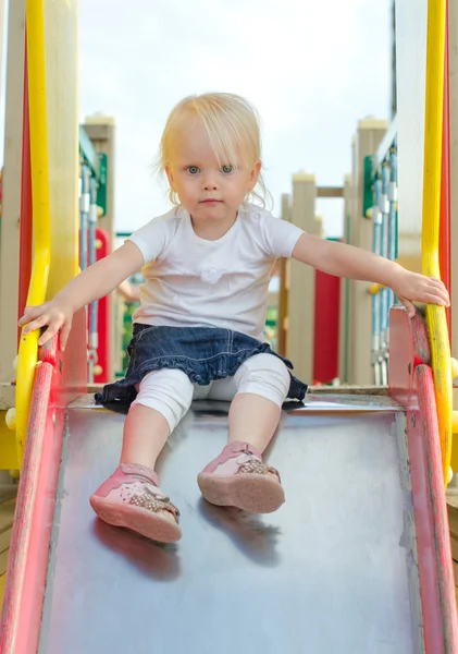 Niña en el tobogán infantil en el patio de recreo —  Fotos de Stock