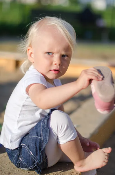 Criança colocar em seus sapatos perto sandbox — Fotografia de Stock