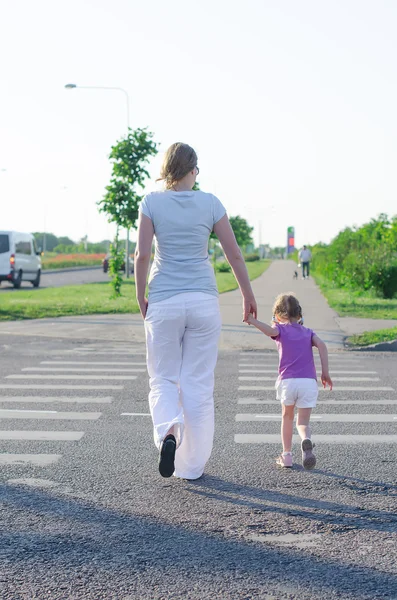 Moeder en kind kruising de weg. Achteraanzicht. — Stockfoto