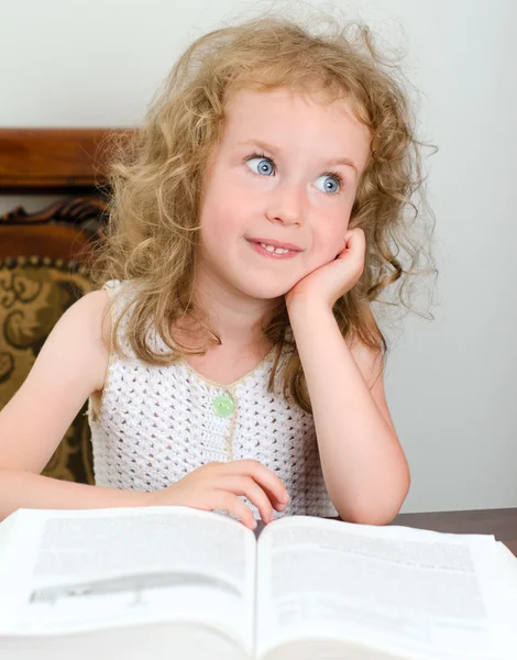 Ładny mały dziewczyna uśmiechający się czytając książkę — Zdjęcie stockowe