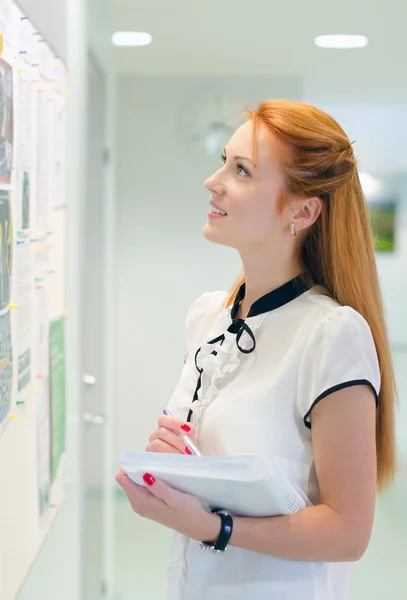 Young female student looking through job offers on board — Stock Photo, Image