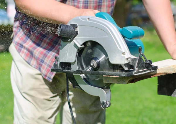 Handyman utilizando la máquina de sierra de mano al aire libre — Foto de Stock