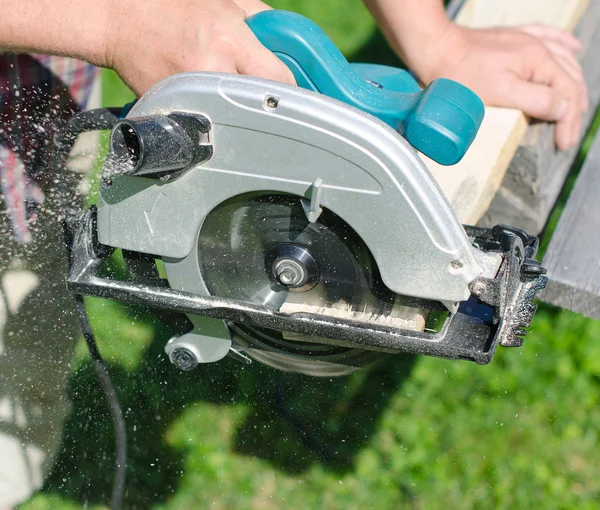 Handyman usando máquina de serra de mão ao ar livre — Fotografia de Stock