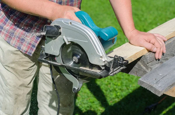 Handyman usando máquina de serra de mão ao ar livre — Fotografia de Stock