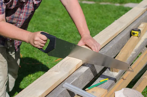 Handyman serrar prancha de madeira longa ao ar livre — Fotografia de Stock
