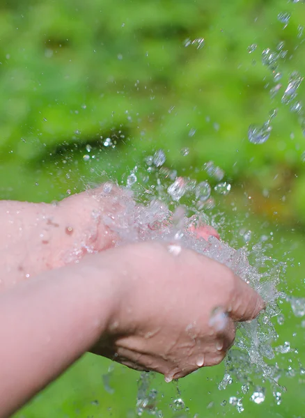 Las manos de la mujer con agua salpicada al aire libre — Foto de Stock