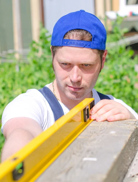 Young handyman using spirit level outdoors — Stock Photo, Image