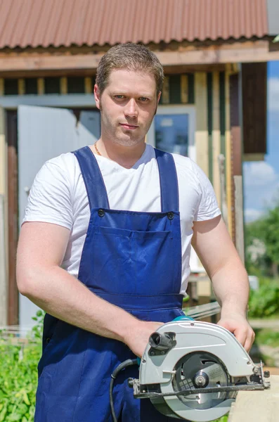 Handyman using hand-held saw machine outdoors — Stock Photo, Image