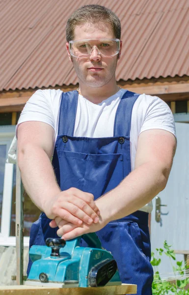 Klusjesman met behulp van elektrische planer buitenshuis — Stockfoto