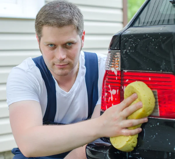 Jonge werknemers wassen auto met gele spons — Stockfoto