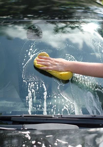 Vrouwelijke hand met gele spons wassen auto — Stockfoto