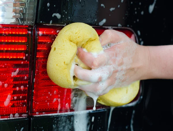 Mano femminile con spugna gialla lavaggio auto — Foto Stock