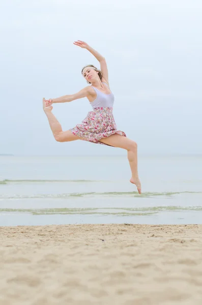 Giovane donna in salto su una riva del mare — Foto Stock