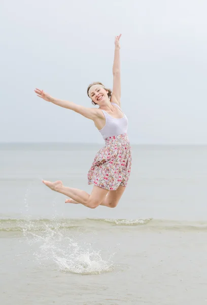 Mutlu kadın deniz kıyısında atlama — Stok fotoğraf