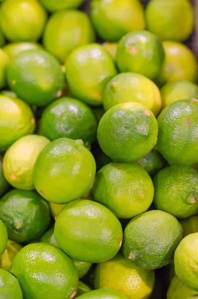 Un montón de limas verdes brillantes en el supermercado — Foto de Stock