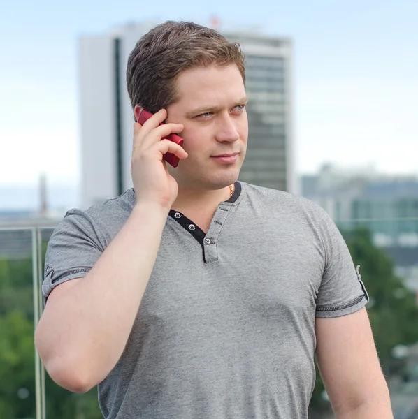 Handsome man speaking on the phone on city background — Stock Photo, Image