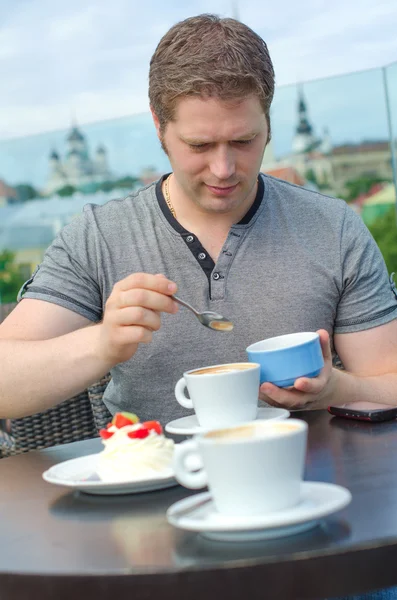Nuori mies levätä kupin kahvia ulkona kahvilassa — kuvapankkivalokuva