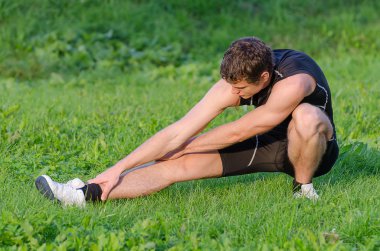 Genç sporcunun parkta egzersiz önce ısınma