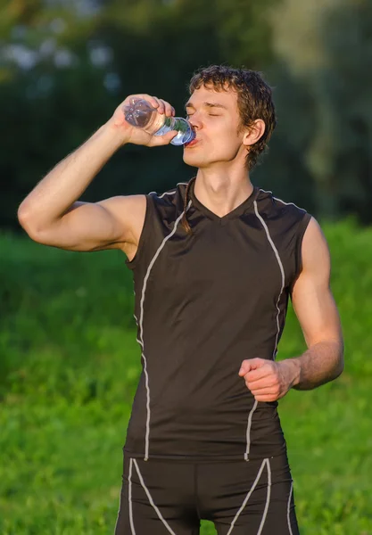 Sportsman dricksvatten från flaska efter träning — Stockfoto