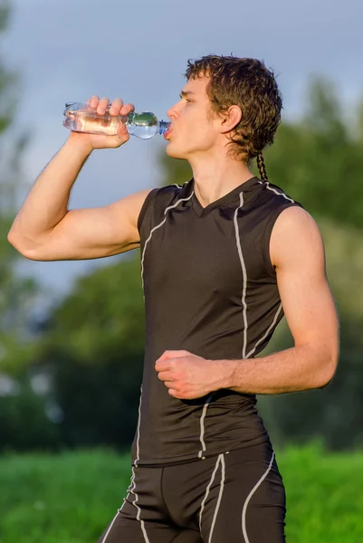 Sportsman drinking water from bottle after workout — Stock Photo, Image