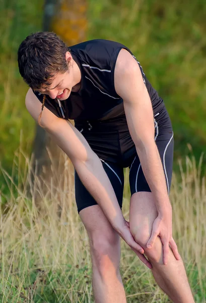 그의 다리를 잡고 스포츠맨입니다. 스포츠 부상 개념. — 스톡 사진