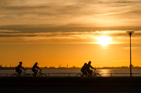 Sunset over the sea with bicyclist silhouettes — Stock Photo, Image