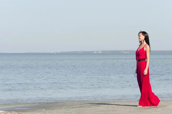 Kobieta w czerwonej sukience stoi na plaży. miejsce dla tekstu — Zdjęcie stockowe