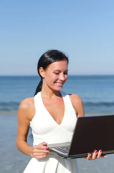 Attraktiv kvinna med bärbara på stranden. plats för text — Stockfoto