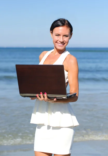 Aantrekkelijke vrouw met laptop op het strand — Stockfoto