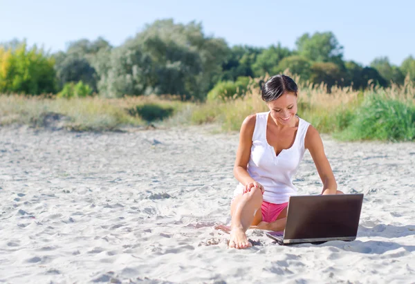 Attraktiv kvinna med laptop arbetar på stranden. plats för text — Stockfoto