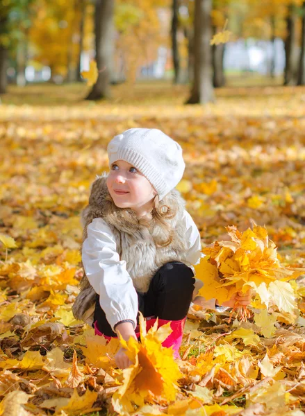 A kislány őszi leveleket gyűjt.. — Stock Fotó