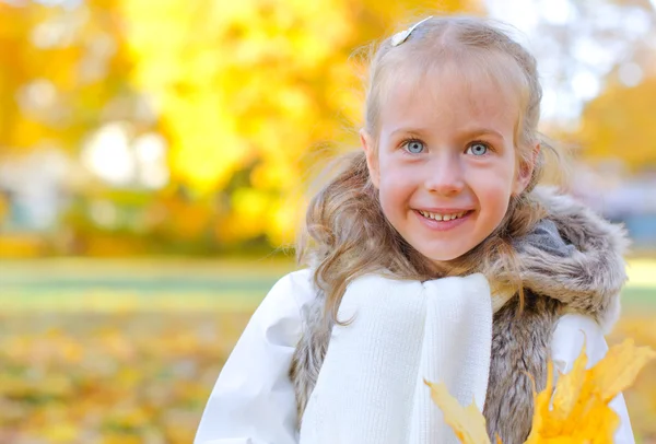 Little smiling girl with fallen autumn leaves. Space for text. — Stock Photo, Image