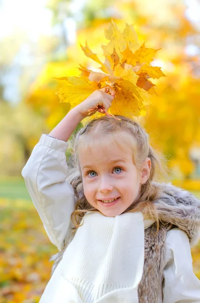 Kleines Mädchen spielt mit fallenden Herbstblättern. — Stockfoto