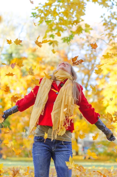 Donna felice gettando foglie d'autunno nel parco . — Foto Stock