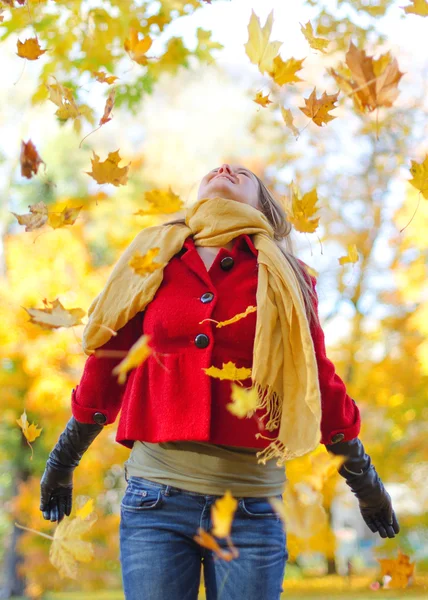Szczęśliwa kobieta rzucająca jesienne liście w parku. — Zdjęcie stockowe