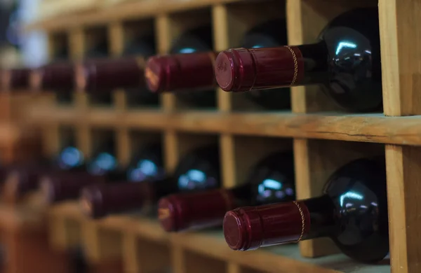 Red wine bottles stacked on wooden racks — Stock Photo, Image