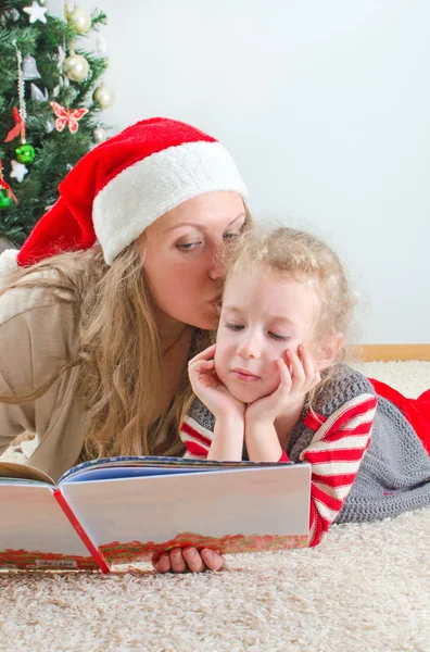 Little girl and her mom reading book at Christmas — Stock Photo, Image